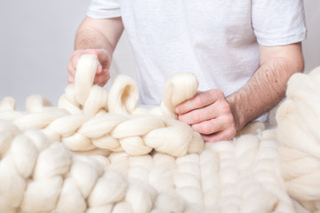Obraz na płótnie Canvas men's hand knit with thick yarn plaid. man knits.