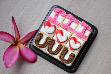 Cakes with cream hearts and a frangipani flower. The writing I love you on cakes.