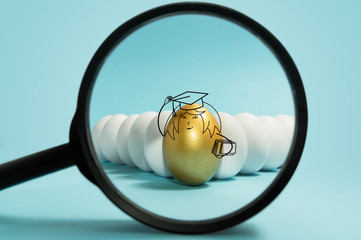 Business recruitment, talent management. One golden egg with graduation cap under magnifier among white eggs on blue background.