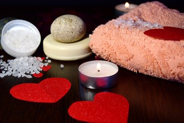 Valentine's day Spa style. a dark table on which one heart of bath salt is removed at 45 degrees with rose petals, a towel and cream. selective focus