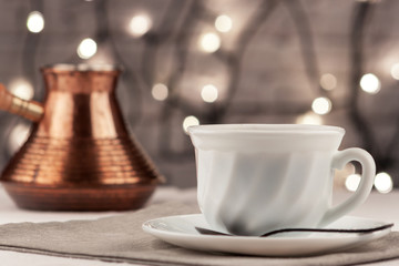 On the table are a cup of fresh aromatic coffee and a copper Turk for brewing coffee