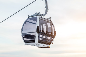 Cabin of a gondola cableway suspended on a rope where sits people with skis and snowboards high in the Altai mountains with snow and blue sky on winter sunset. Ski resorts and snowboarding. © Aleksandr Kondratov