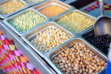 A view of several containers full of raw fresh beans on display at a local farmers market.