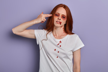 injured girl with closed eyes holding her hand, palm like a pistol near her temple, pretending killing herself, close up portrait, crime, studio shot.