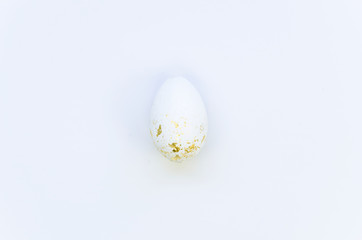 Closeup up top view white egg with real gold foil leaf pieces for Easter. High-class trendy Easter Holiday card on a white background