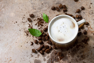 Morning coffee concept. Cup of coffee latte and coffee beans on a stone old concrete countertop. Copy space.