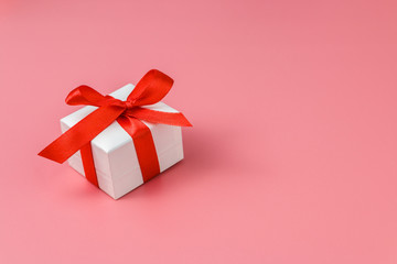 white gift box with red strap on colour background, engagement ring box