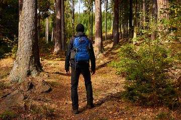 Mann steht mit Rucksack im Wald