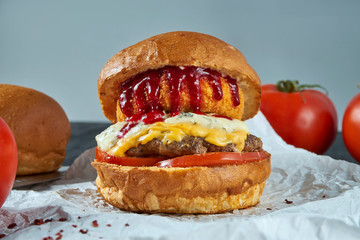 Tasty and juicy burger with three different cheese: blue cheese, camembert fries and cheddar on parchment. Fast food, street food.