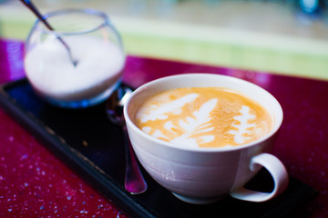 mug of hot cappuccino coffee on a stand with sugar