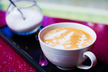 mug of hot cappuccino coffee on a stand with sugar