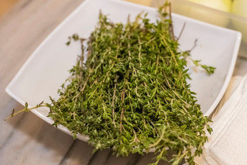 Green thyme in a white bowl on a board, closeup