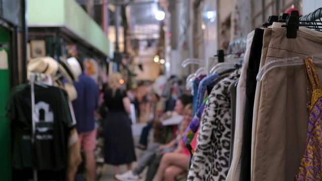 A clothing rack in a second hand store and defocused people on background