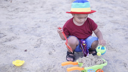 Fototapeta premium Cute baby boy playing with beach toys on tropical beach happy kid outdoor holiday.