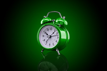 Green alarm clock with reflection on glass close-up isolated on dark background with green gradient.