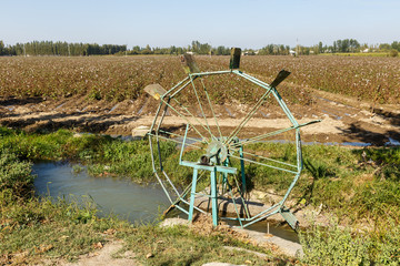 Water turbine on a cotton field. Water wheel and channel for watering plants on the field