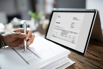 Businessman's Hands Working On Invoice On Laptop