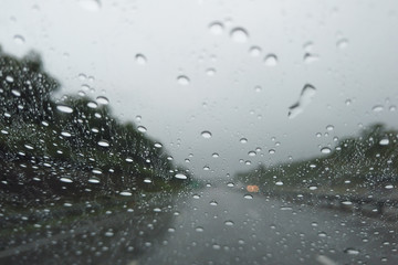Rain drop falling on car windshield, drive car on street in city in heavy rain