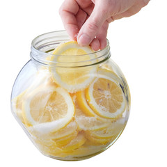 Woman's hand puts slice of lemon in can isolated on white background.