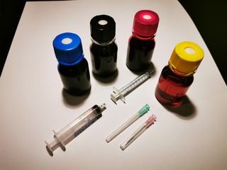 tubes of paint and brushes Refill inks for printers and copiers with blue, red, yellow and black ink in bottles with syringes to pull on and needles on a white background and black background