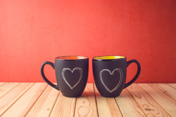 Valentines day concept with chalkboard coffee mugs and heart shapes on wooden table.