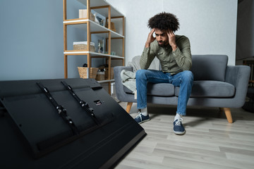 Man Sitting On Sofa In Front Fallen Television