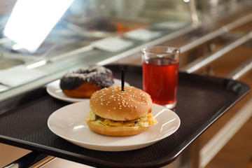 Plastic tray with tasty food near serving line in school canteen