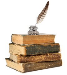 Isolated books. Glass inkwell and quill on top of old books stack isolated on white background with...