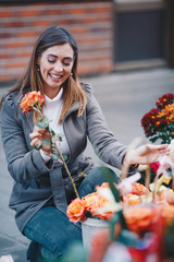 Beautiful young Caucasian woman buying flowers at local market.