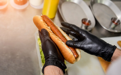 The chef cooking hot dog on a grill. Restaurant.