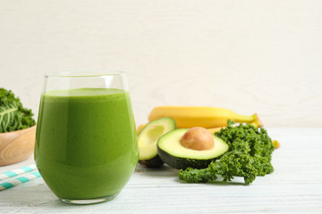 Tasty fresh kale smoothie on white wooden table