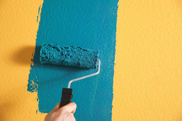 Man painting yellow wall with blue dye, closeup