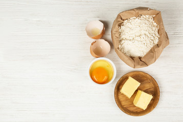 Flat lay composition with eggs and other ingredients  on white wooden table, space for text. Baking pie