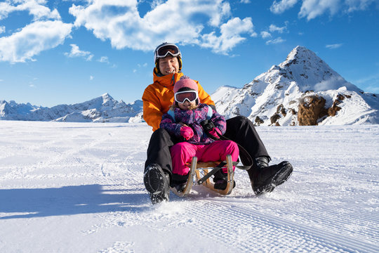 Father And Daughter Playing On Sled