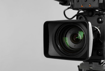Modern professional video camera on light background, closeup