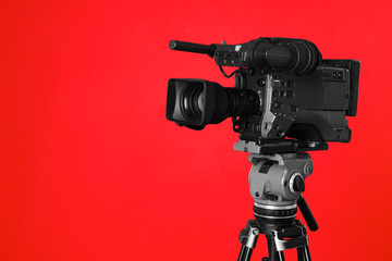 Modern professional video camera on red background