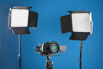 Professional video camera and lighting equipment on blue background