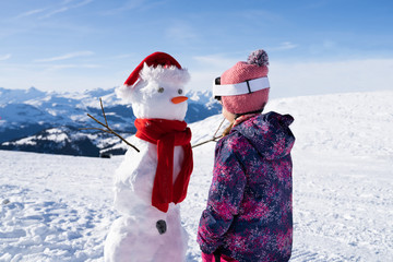 Little Girl Standing In Front Of Snowman