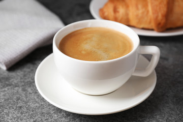 Tasty fresh croissant and coffee on grey table, closeup