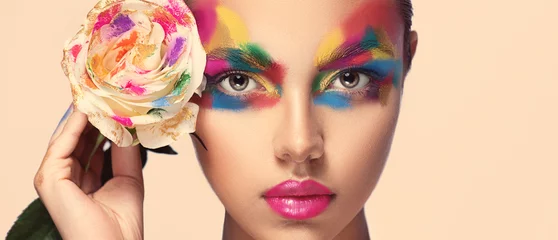 Peel and stick wall murals Beauty salon Beautiful girl model with multi-colored paints on her face. Woman with rose flower and bright color make-up. Cosmetics, beauty and makeup.  Spring and summer flowering  shopping