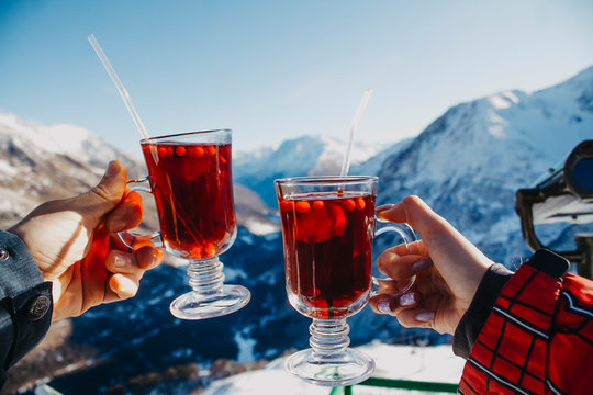 Two glasses with mulled wine close-up in the hands on a background of mountains.