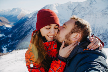 Closeup portrait of lovers man and woman in the mountains. A man kisses a woman, a young woman smiles with her eyes closed.