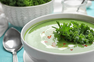 Tasty kale soup on light blue wooden table, closeup