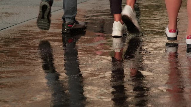 People walking on wet pavement on rainy day. Close up of feet. 4K resolution. 