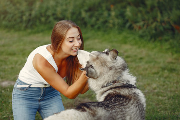 Beautiful girl in a white t-shirt. Woman in a summer park. Lady with a dog