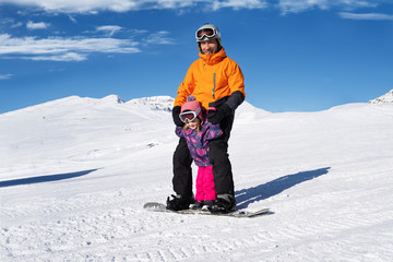 Fototapeta na wymiar Father Riding Snowboard With His Daughter