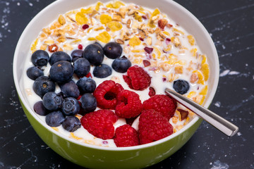 Close up of a bowl of cereal in milk, supplemented with fresh blueberries and raspberries.