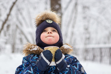 boy drinks a hot drink in a handsome winter forest