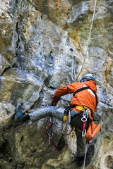 Obraz premium Rappelling a vertical cliff by a climber. Extreme outdoor