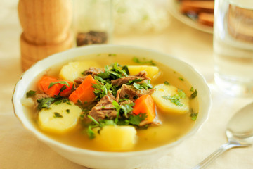 Lamb soup. Meat soup with vegetables. Dishes of Oriental cuisine. Traditional lunch in summer, homemade shurpa soup on a light table